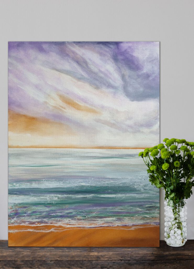 The coast/sea painting standing on the wooden floor, next to a flower vase.