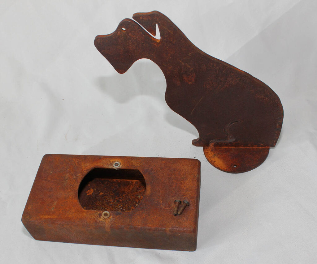 An oxidised steel dog urn standing inside. The urn box is lieing seperate from the figure.