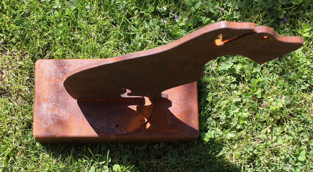 Oxidised steel dog urn standing in the garden, viewed from above.