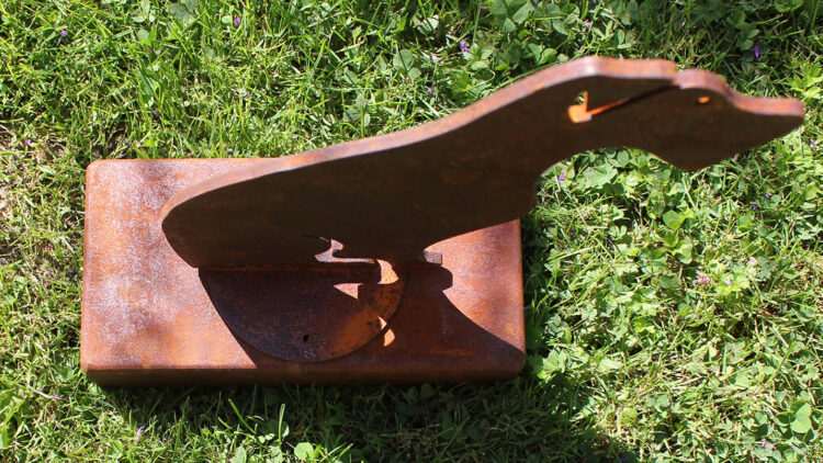 Oxidised steel dog urn standing in the garden, viewed from above.