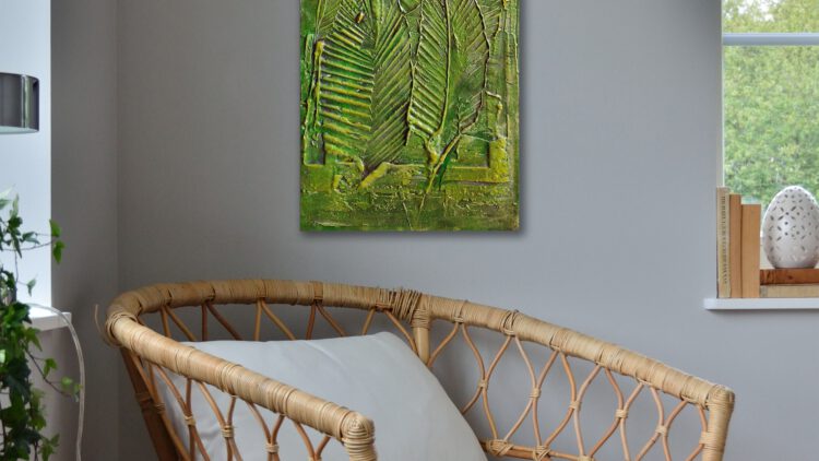 A painting of big leafs hanging on the wall of the corner of a grey room.