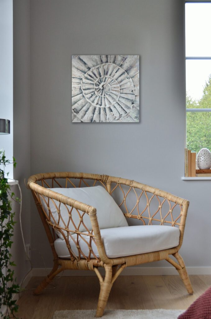 The painting of the shell hanging on a wall, in the corner of a room. The paintings colours pair well with the grey and wood-tones in the room.