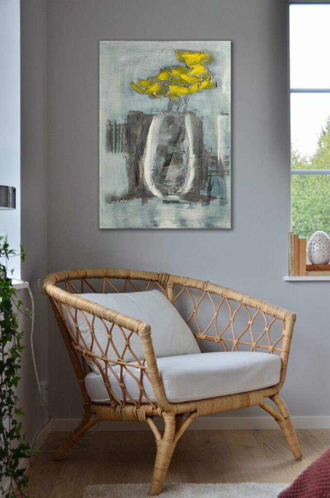 The painting of yellow flowers in a vase hanging on the wall in the corner of a room.