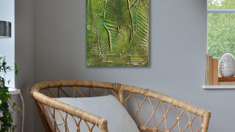 The painting of big leafs hanging on the wall of the corner of a grey room.